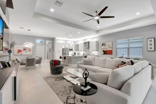 living room with ceiling fan and a raised ceiling