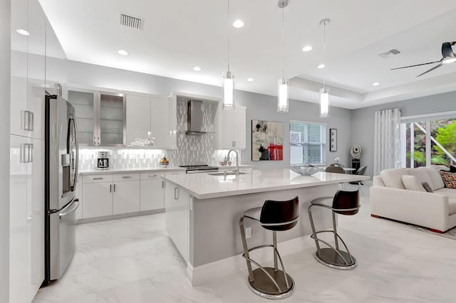 kitchen featuring a breakfast bar, sink, white cabinets, and stainless steel refrigerator with ice dispenser