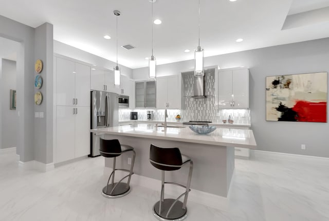 kitchen with a kitchen bar, white cabinetry, stainless steel appliances, and hanging light fixtures