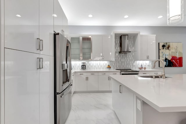 kitchen with decorative backsplash, white cabinetry, wall chimney exhaust hood, and sink