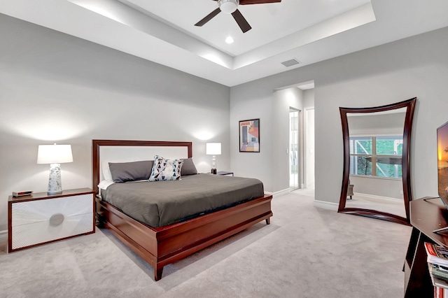 carpeted bedroom with a tray ceiling and ceiling fan