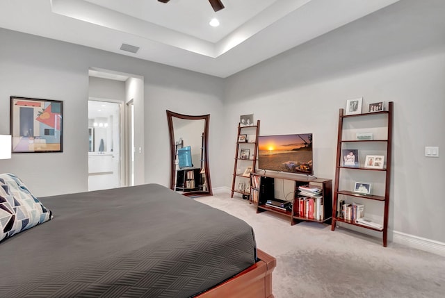 bedroom featuring ceiling fan, light carpet, and a tray ceiling