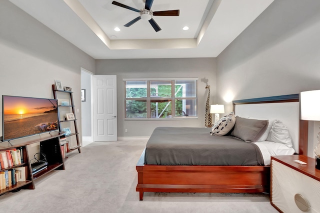 bedroom featuring light colored carpet, a raised ceiling, and ceiling fan