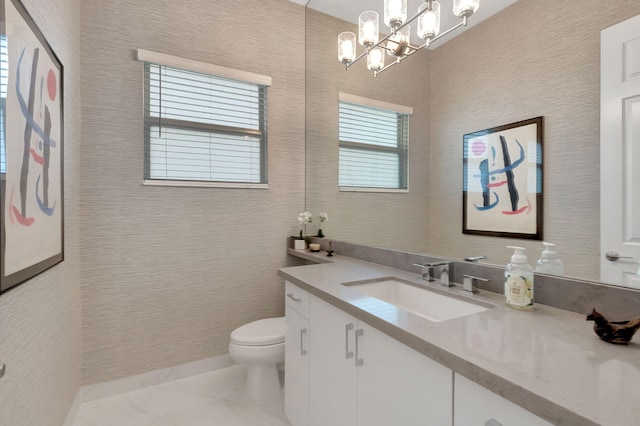 bathroom featuring vanity, toilet, and a notable chandelier