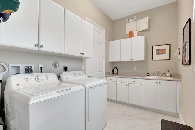 clothes washing area with washing machine and clothes dryer, sink, and cabinets