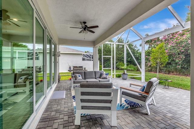 view of patio with outdoor lounge area, ceiling fan, and glass enclosure