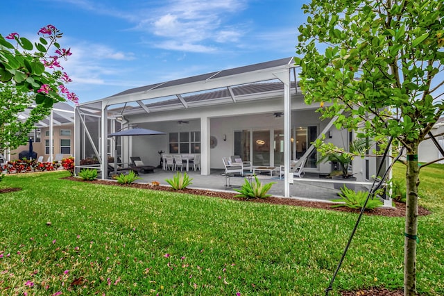 rear view of house featuring a lawn, ceiling fan, a patio area, and a lanai