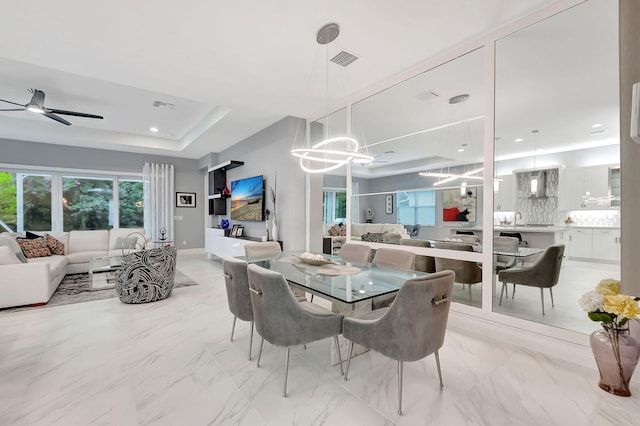 dining room with a raised ceiling and ceiling fan