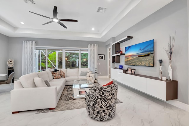 living room featuring a raised ceiling, ceiling fan, and built in features