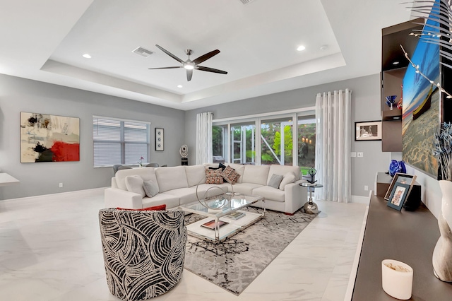 living room with a tray ceiling and ceiling fan