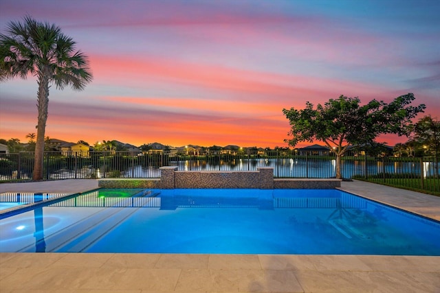 pool at dusk featuring a jacuzzi and a water view