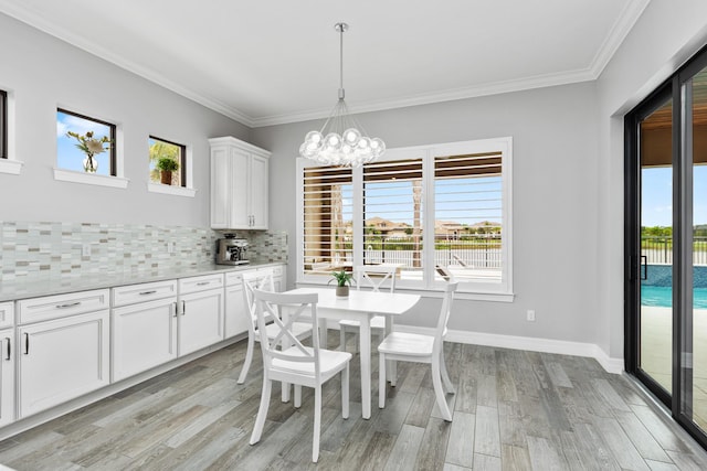 dining room with light hardwood / wood-style floors, crown molding, and a notable chandelier