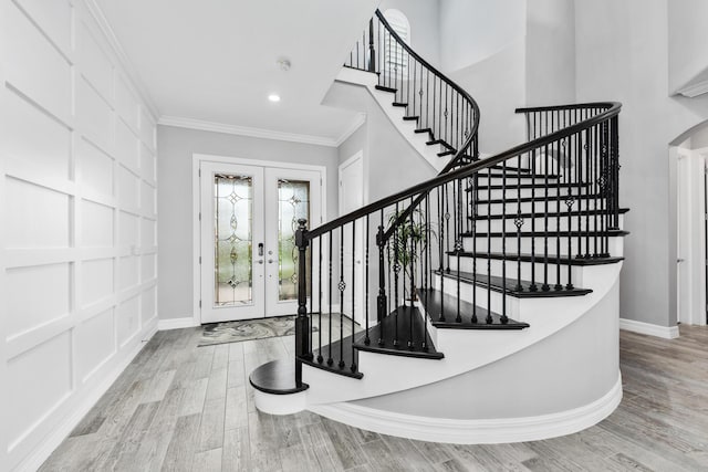 entrance foyer with french doors, ornamental molding, and light wood-type flooring