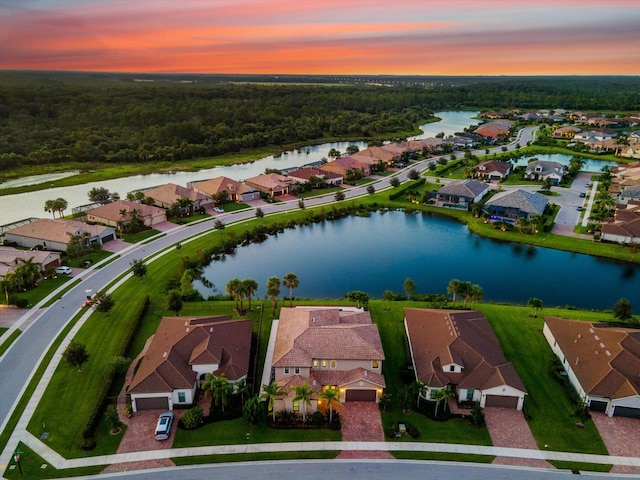 aerial view at dusk featuring a water view