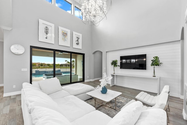 living room with a towering ceiling, a chandelier, and hardwood / wood-style flooring