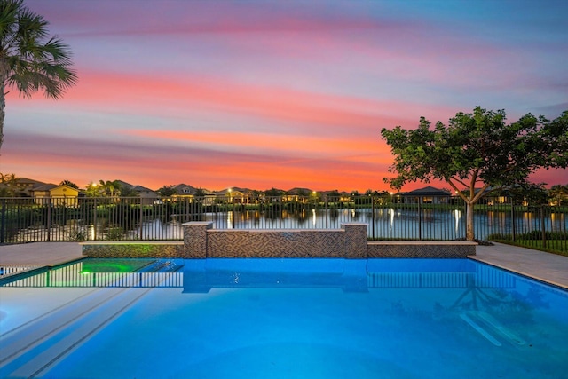 pool at dusk featuring a water view