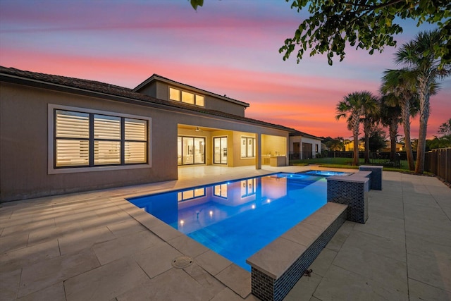 pool at dusk with an in ground hot tub, ceiling fan, and a patio area