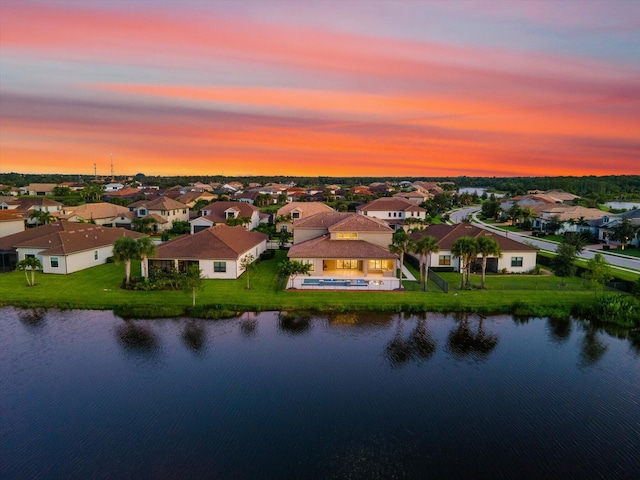 aerial view at dusk featuring a water view