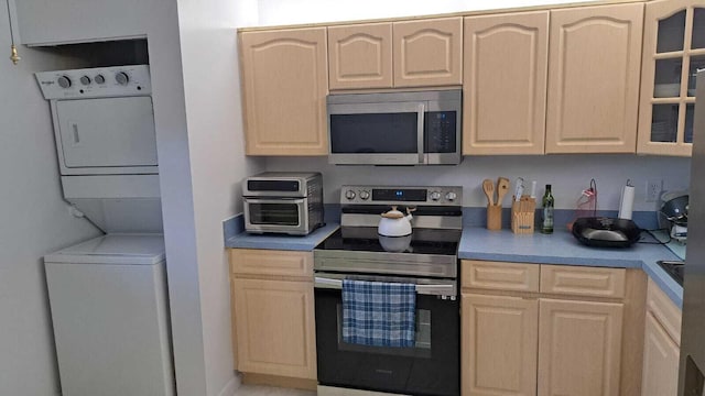 kitchen with light brown cabinetry, stainless steel appliances, and stacked washer and clothes dryer