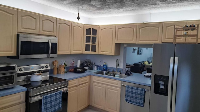 kitchen featuring light brown cabinetry, sink, stainless steel appliances, and a textured ceiling