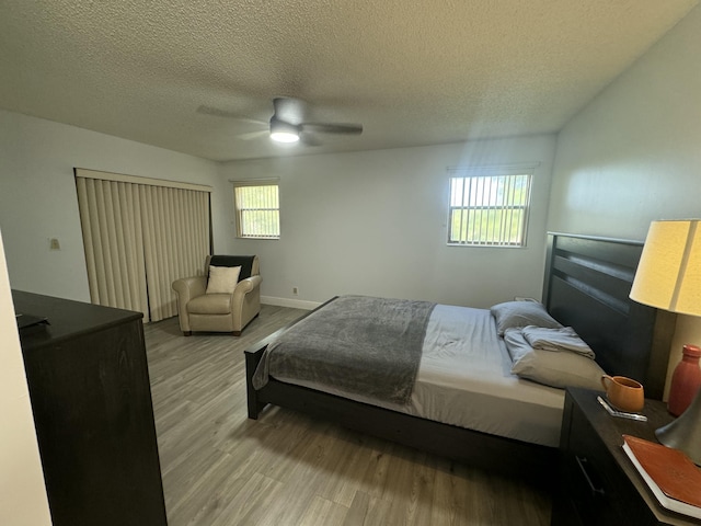 bedroom featuring multiple windows, a textured ceiling, light hardwood / wood-style flooring, and ceiling fan