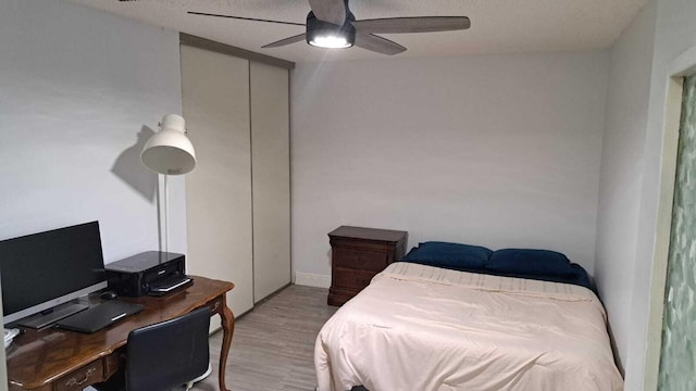 bedroom featuring a textured ceiling, a closet, light hardwood / wood-style floors, and ceiling fan