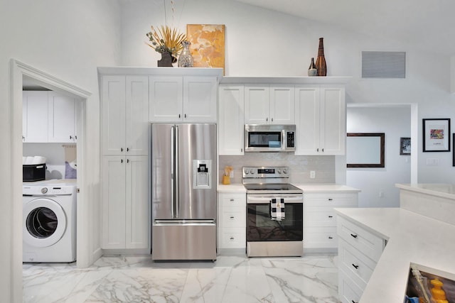 kitchen with lofted ceiling, backsplash, white cabinets, washer / dryer, and stainless steel appliances