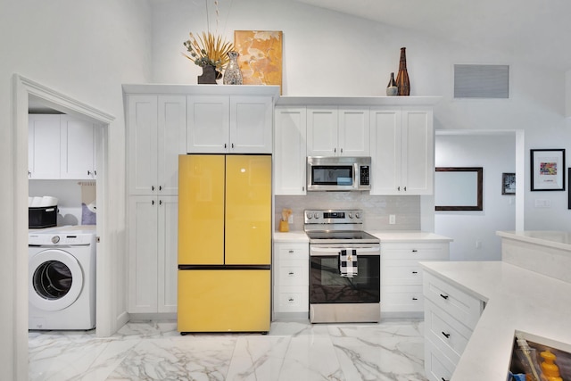 kitchen with white cabinets, appliances with stainless steel finishes, decorative backsplash, and washer / dryer