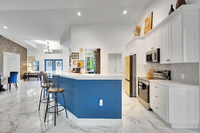 kitchen featuring a center island with sink, a kitchen breakfast bar, decorative backsplash, appliances with stainless steel finishes, and white cabinetry