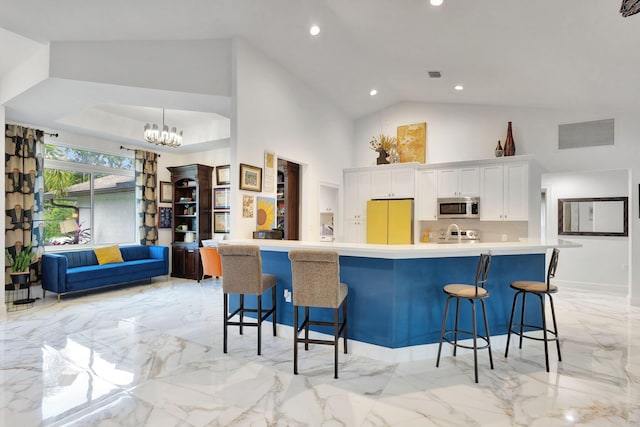 kitchen with a breakfast bar, white refrigerator, high vaulted ceiling, white cabinets, and a chandelier