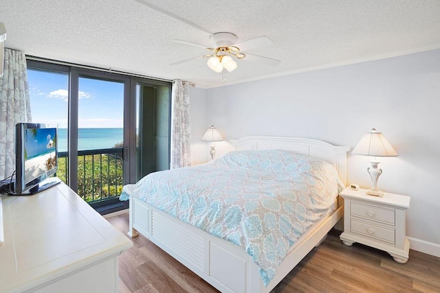 bedroom featuring multiple windows, ceiling fan, wood-type flooring, and a textured ceiling