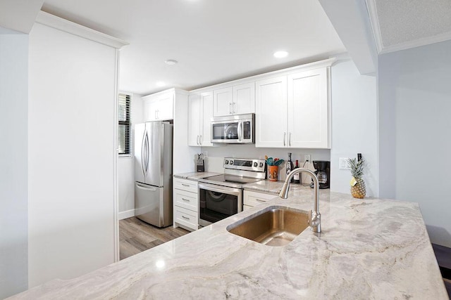 kitchen featuring white cabinets, crown molding, sink, light stone countertops, and appliances with stainless steel finishes