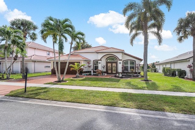 mediterranean / spanish-style home with french doors, a front lawn, and a garage