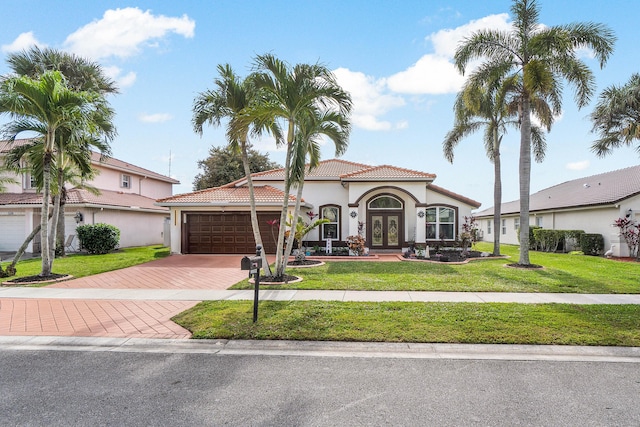 mediterranean / spanish house with a garage, a front lawn, and french doors