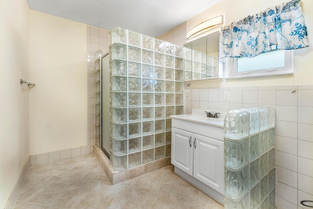 bathroom featuring tile patterned floors, tiled shower, vanity, and tile walls