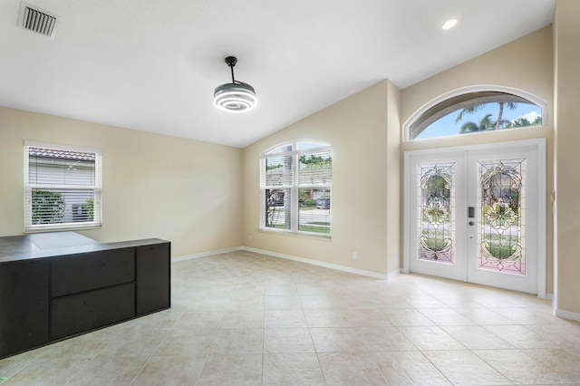 tiled foyer featuring lofted ceiling and french doors