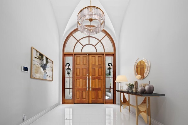 tiled foyer entrance with high vaulted ceiling and a chandelier