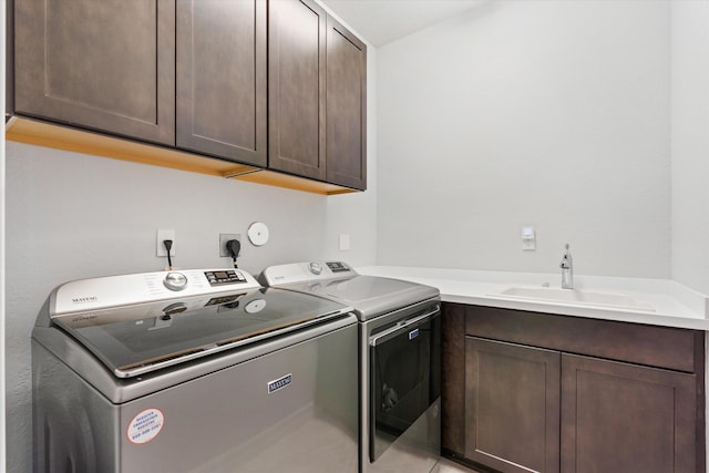 washroom featuring washing machine and dryer, sink, and cabinets