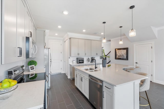 kitchen with a center island with sink, white cabinets, sink, decorative light fixtures, and stainless steel appliances