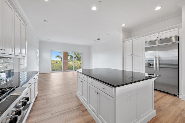 kitchen featuring white cabinets, ornamental molding, a center island, and high quality appliances