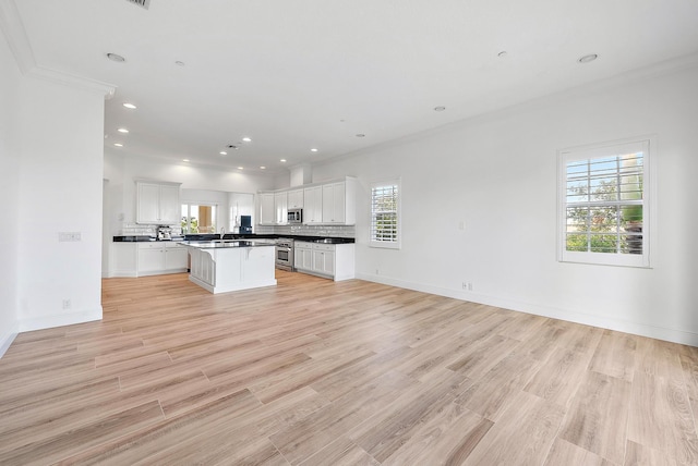 kitchen featuring a kitchen island, ornamental molding, tasteful backsplash, light hardwood / wood-style floors, and white cabinetry