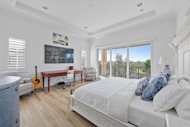 bedroom featuring access to exterior, a tray ceiling, crown molding, and light hardwood / wood-style floors