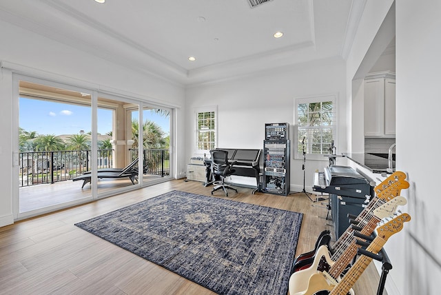 office area with light hardwood / wood-style floors, a raised ceiling, and ornamental molding