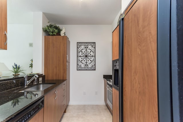 kitchen with dishwashing machine, dark stone countertops, brown cabinetry, a sink, and high end refrigerator