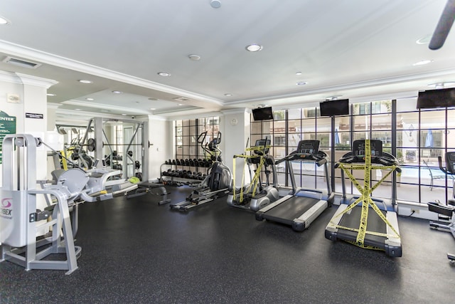 gym with a raised ceiling and ornamental molding