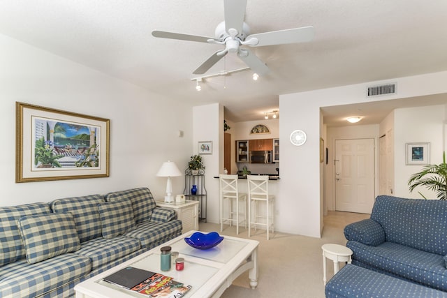 living room with visible vents, light colored carpet, and ceiling fan