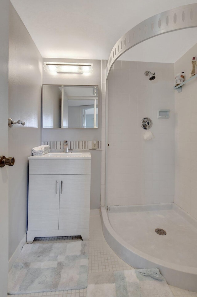 bathroom featuring a tile shower, vanity, and tile patterned flooring