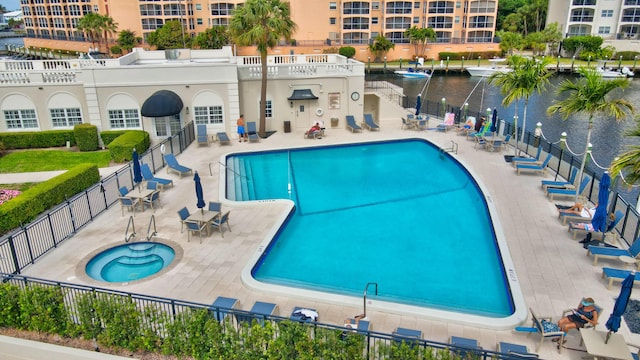 view of swimming pool featuring a community hot tub, a water view, and a patio area