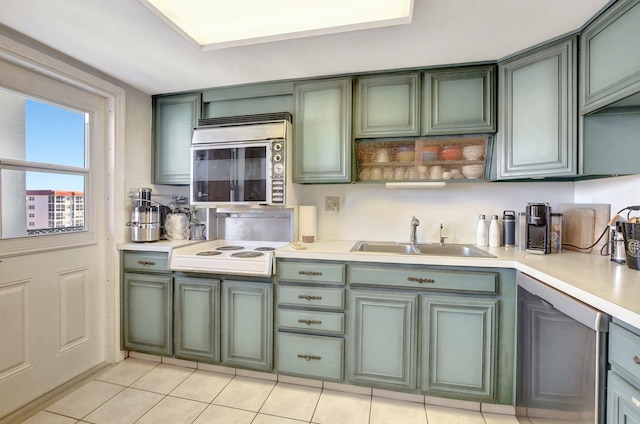 kitchen with appliances with stainless steel finishes, sink, light tile patterned floors, and green cabinetry