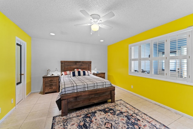 bedroom with ceiling fan, light tile patterned floors, and a textured ceiling